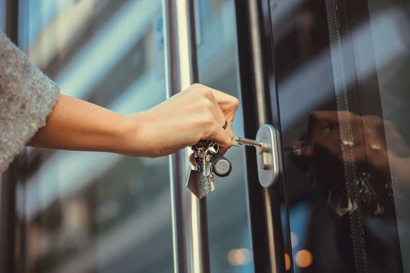 Commercante en train d'ouvrir la porte blindée de son commerce et magasin